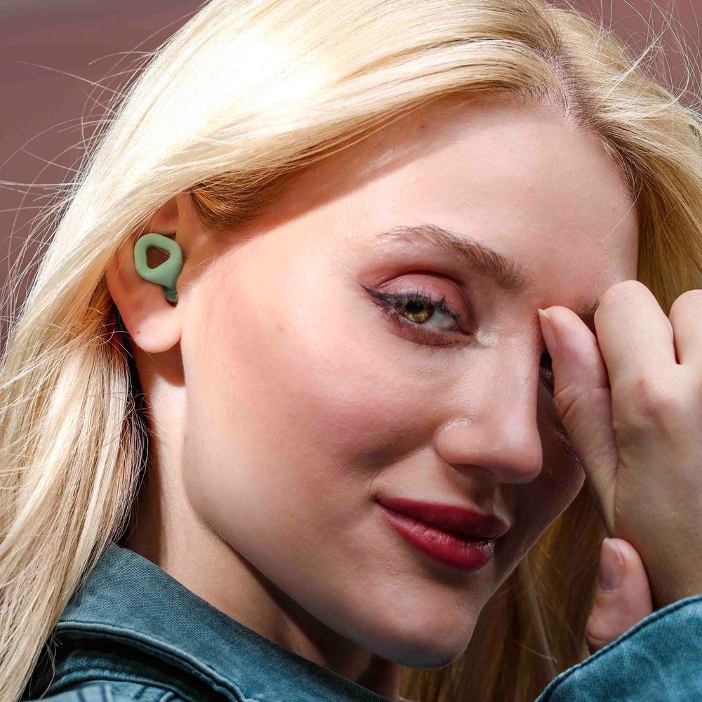 Woman wearing Zenz Unwind mint green earplugs, showcasing the stylish and comfortable fit for noise reduction